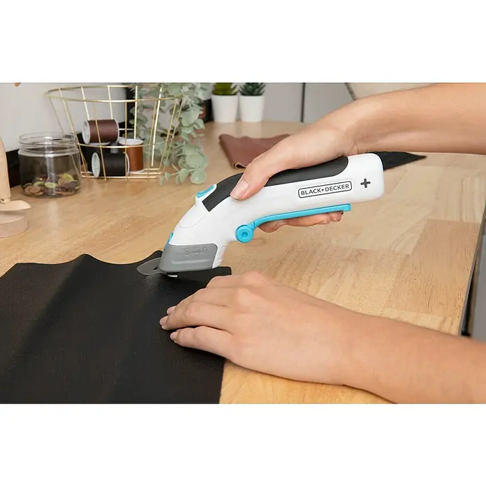 Black+Decker Grapadora de batería BCN115-XJ-Li - 3,6 V, 1 batería, 1,5 Ah - Primer plano de una persona que utiliza unas tijeras eléctricas Black+Decker para cortar un trozo de tela negra. Herramienta de corte de precisión.