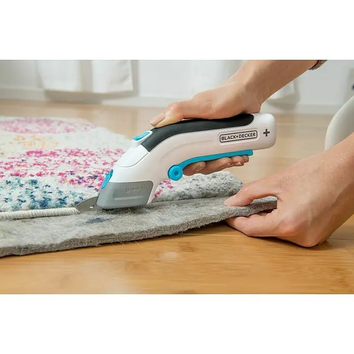 Black+Decker Grapadora de batería BCN115-XJ-Li - 3,6 V, 1 batería, 1,5 Ah - Tijeras multiusos Black+Decker cortando una alfombra sobre un piso de madera.