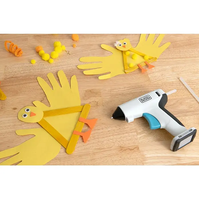 Black+Decker Pistola termoencoladora con batería BCGL115 3,6V-Li - 3,6 V - Primer plano de una pistola de pegamento BLACK+DECKER, ideal para proyectos de manualidades como los pollitos amarillos con huellas de manos en la mesa.