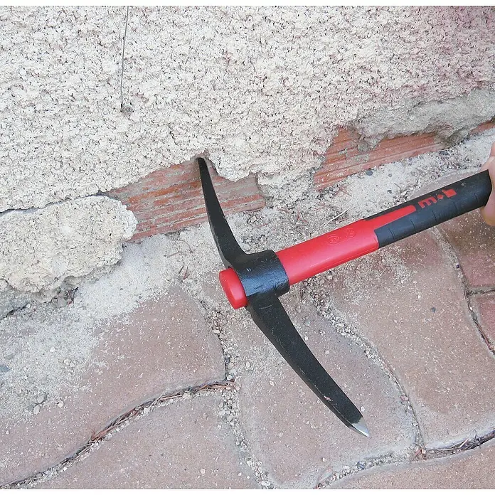 Peddinghaus Kreuzhacke - Länge: 37,5 cm, Stahl - Nahaufnahme eines Maurerhammers mit rotem Griff, der zum Entfernen von Putz von einer Ziegelmauer verwendet wird.