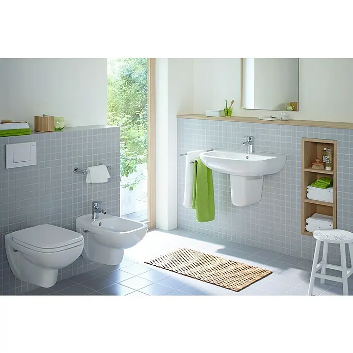 Duravit D-Code Waschtisch - 65 x 50 cm, Ohne Spezialglasur, Hahnloch: Mitte, Mit Überlauf, Weiß - Das Bild zeigt ein helles Badezimmer mit einer wandhängenden Toilette und Bidet, einem Waschbecken und einem Holzregal.