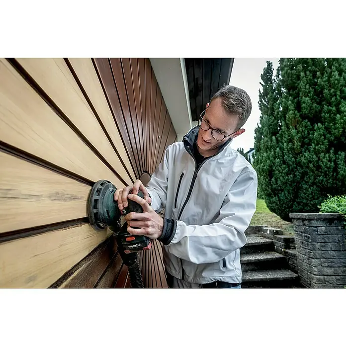Metabo CAS 18V Akku-Exzenterschleifer SXA 18 LTX 150 BL - 18 V, Durchmesser Schleifteller: 150 mm - Mann schleift Holzfassade mit einem Metabo Exzenterschleifer, um sie für die nächste Behandlung vorzubereiten. Perfekt für Renovierungsarbeiten.