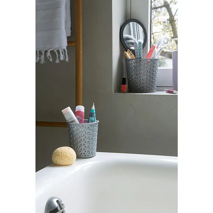 Curver Allzweck-Korb My Style - Ø x H: 10,6 x 11,2 cm, Grau - Badezimmer-Szene mit einem grauen Behälter gefüllt mit Beauty-Produkten auf einer Badewanne, neben einem Holzregal und Fenster.