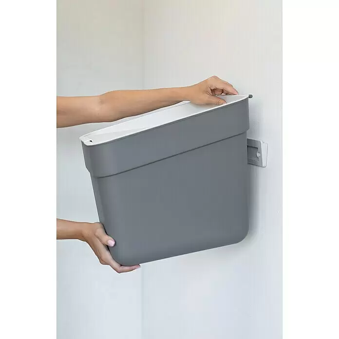 Curver Standard Mülleimer Ready to Collect - 20 l, Kunststoff, Dunkelgrau - Hände befestigen einen grauen Wandbehälter mit weißer Innenseite.