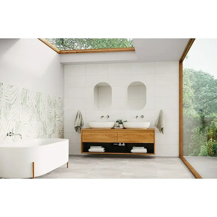 Domicil Feinsteinzeugfliese Living Concrete Pearl - 30 x 60 cm, Beige, Matt - Ein Badezimmer mit einer Badewanne, einem Waschtisch mit zwei Waschbecken und großen Fenstern, die einen Blick auf die Natur bieten.