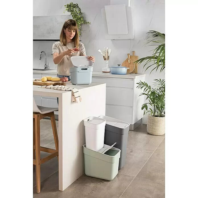Curver Standard Mülleimer Ready to Collect - 10 l, Kunststoff, Weiß - Hellblauer Küchen-Komposteimer, von einer Frau für Essensreste genutzt. Drei weitere Recyclingbehälter in Weiß, Grau und Grün sind sichtbar.