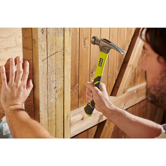 Ryobi ONE+ Taladro atornillador percutor de batería + caja herramientas y accesorios R18PD3-220TAH - 18 V, 2 baterías, 2 Ah, 50 Nm - Primer plano de un hombre clavando un clavo en una tabla de madera con un martillo Ryobi, destacando el martillo.