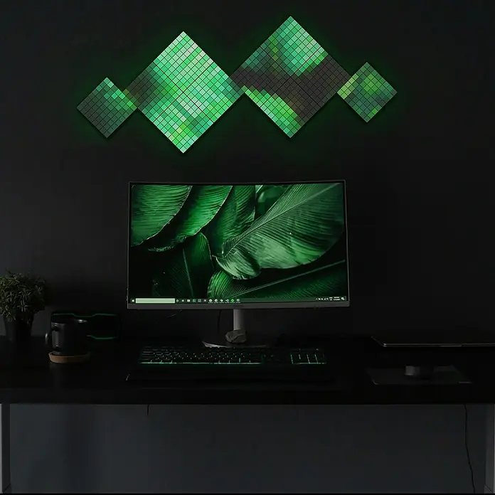 Twinkly LED-Panel-Set Squares RGB StartersetRGB - Ein Gaming-Setup mit einem Monitor, einer Tastatur und einer Wanddekoration mit grünen Lichtpaneelen, die eine entspannende Atmosphäre schaffen.