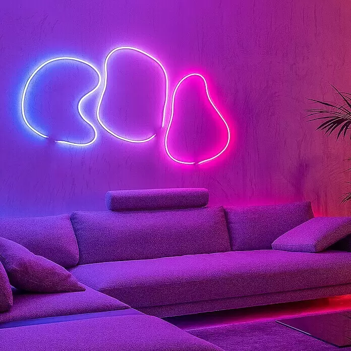 Twinkly LED-Lichtschlauch Flex - Länge: 2 m, Lichtfarbe: RGB, 15 W - Großes lila Ecksofa in einem lebhaften Raum mit blauen und pinken Neonlichtern. Das Sofa hat einen strukturierten Stoff und Kissen.