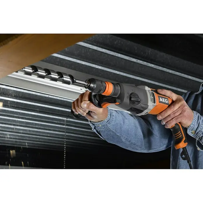 AEG Powertools Kombihammer KH 28 Super XE - 1.010 W, 2,8 J, SDS-Plus-Aufnahme - Nahaufnahme einer AEG Bohrmaschine beim Bohren in Holz, ideal für Bau- und Renovierungsprojekte, für präzise und kraftvolle Ergebnisse.