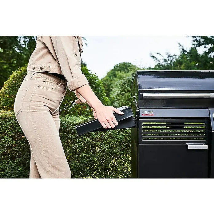 Char-Broil Elektrogrill Smart E - Grillfläche (B x T): 57 x 39 cm, 2,4 kW - Eine Person, die eine schwarze SMART-E TRU-Infrared Grillkomponente in einen Grill einsetzt, vor einem grünen Hintergrund.