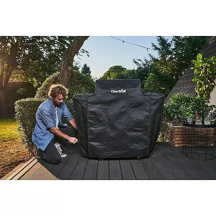 Char-Broil Grill-Schutzhülle - Passend für: Char-Broil Elektrogrill Smart E, Polyester - Ein Mann deckt einen Char-Broil Grill mit einer schwarzen Stoff-Grillabdeckung auf einer Holzterrasse ab.