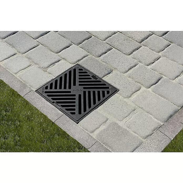 ACO Self Hofablauf mit Gussrost - 25 x 25 x 36 cm, Herausnehmbarer Schlammeimer - Schwarzer ACO Abflussrost in grauen Pflastersteinen eingelassen.
