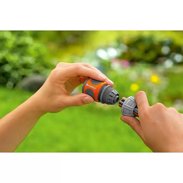 Gardena Schlauchkupplung - ½″ / ⁵⁄₈″ - Hände verbinden einen orange-grauen Gardena Schlauchverbinder für den Garteneinsatz.