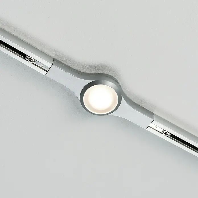 Paulmann URail Linienverbinder LED - 5,8 W, Chrom matt, L x B x H: 22,5 x 5,7 x 2,7 cm - Nahaufnahme einer modernen, silbernen LED-Schiene mit einem runden Strahler, der helles Licht auf eine weiße Oberfläche wirft.