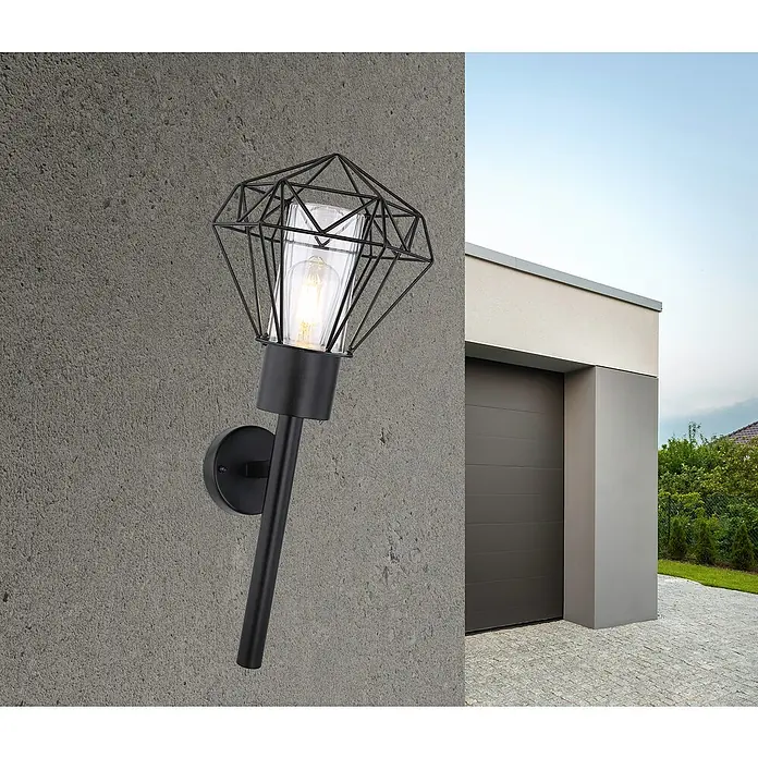 Globo Horace Außenwandleuchte - 15 W, L x B x H: 22,5 x 22,5 x 28,5 cm, Schwarz, IP44, Nicht Dimmbar - Wandleuchte mit schwarzem Metalldiamant-Design. Sie montiert an einer Betonwand vor einer modernen Garage, die ein warmes Licht ausstrahlt.