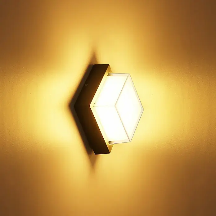 Globo Aplique exterior LED Jalla - 12 W, Gris, IP54 - Primer plano de un aplique de pared moderno en forma de diamante con marco dorado, que emite una luz cálida y brillante.