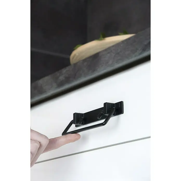 Siro Möbelgriff - Typ Möbelgriff: Sonstige, L x B x H: 146 x 51 x 20 mm, Stahl, Schwarz - Finger berührt schwarzen Schubladengriff an einer weißen Schublade mit grauer Arbeitsplatte.