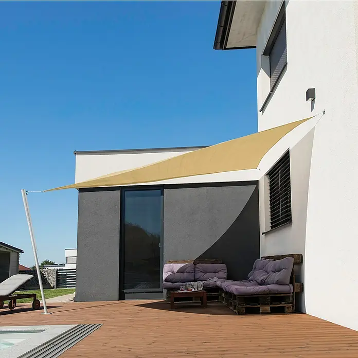 Windhager Sonnensegel Elba - L x B: 3,6 x 3,6 m, Grau, Dreieckig - Blick auf eine Terrasse mit einem Sonnensegel, das Schatten spendet, und Palettenmöbeln, die zum Entspannen einladen.