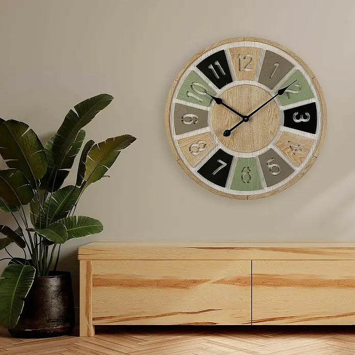 Versa Reloj de pared Madera 60 - Diámetro: 60 cm, Multicolor - Un reloj de pared rústico con bloques de números de colores cuelga sobre un mueble de madera junto a una planta de interior.