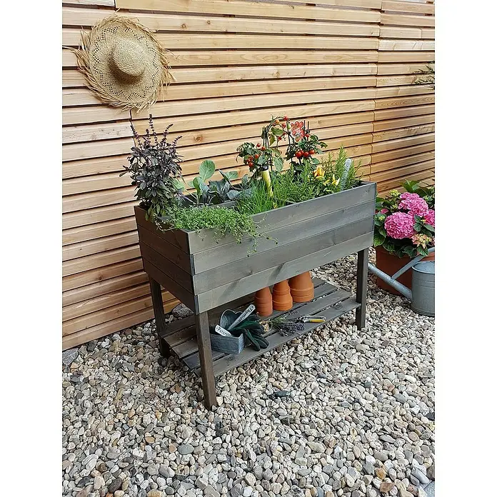 Promadino Kräuterhochbeet - L x B x H: 100 x 50 x 80 cm, Grau - Eine erhöhte Pflanzkiste aus Holz mit Kräutern und Gemüse auf einem Kiesweg vor einer Holzwand.