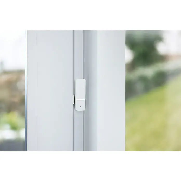 Bosch Smart Home Funk-Fensterkontakt II [+M] Matter - Weiß, Batteriebetrieben, 23 x 22 x 75 mm, 3 Stk. - Nahaufnahme eines weißen Fensterrahmens mit einem montierten, intelligenten Fenster-/Türsensor zur Überwachung.