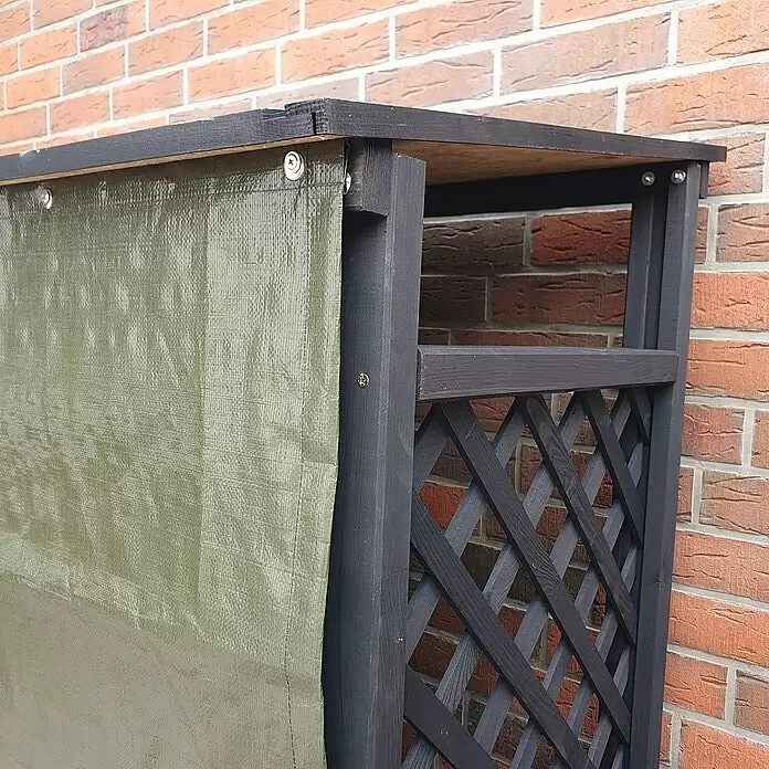 Promadino Kaminholzregal Speyer mit Wetterschutz - 120 x 68 x 148 cm, Anthrazit - Dunkle Holzgitterwand mit grüner wasserdichter Abdeckung, im Freien stehend.