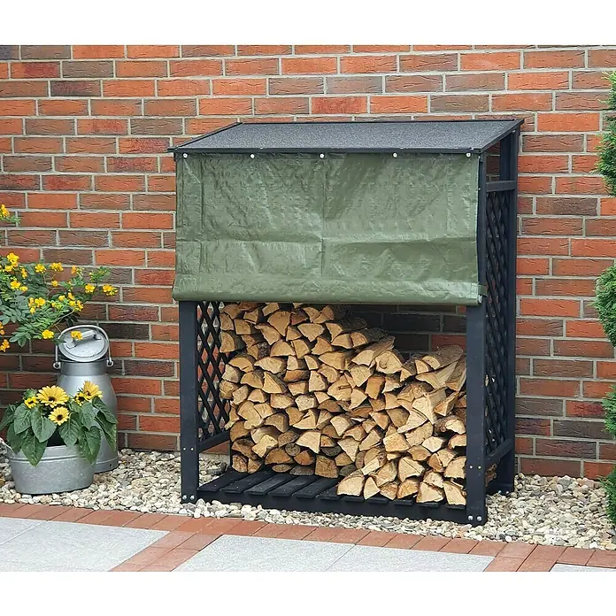 Promadino Kaminholzregal Speyer mit Wetterschutz - 120 x 68 x 148 cm, Anthrazit - Holzunterstand aus schwarzem Metall mit grüner Plane vor einer roten Backsteinmauer mit gestapeltem Brennholz im Unterstand.