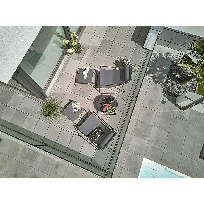 Sunfun Melina Garten-Loungesessel - Stahl/Textilene, Anthrazit, B x T x H: 87,5 x 91,5 x 85,5 cm - Ein hochaufragendes Foto zeigt eine Terrasse mit stilvollen Gartenmöbeln, darunter Stühle und ein Tisch, ideal zum Entspannen im Freien.