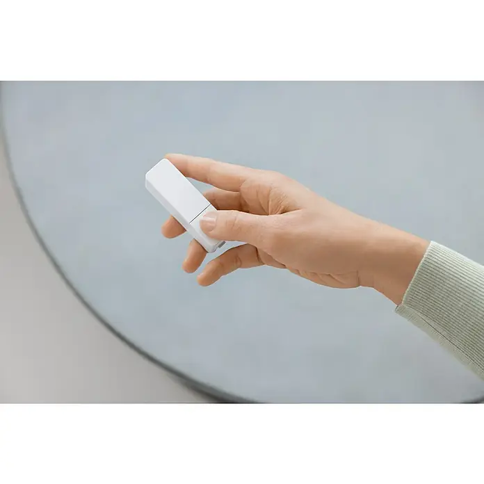 Bosch Smart Home Funk-Fensterkontakt II Plus - Weiß, Batteriebetrieben, 23 x 22 x 75 mm, 2 Stk. - Eine Hand hält einen weißen Zigbee-Schalter, der zur Steuerung von intelligenter Beleuchtung verwendet wird. Praktische Hausautomation für jedes Zuhause.