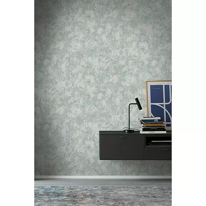 SCHÖNER WOHNEN-Kollektion Vliestapete Patina-Uni - Blau, Betonoptik, 10,05 x 0,53 m - Abstrakte Tapete in Hellblau, Grau und Beige mit strukturierter Oberfläche, an einer Wand in einem modernen Interieur.