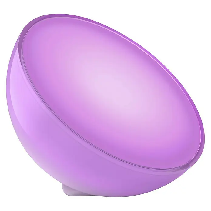 Philips Hue LED-Tischleuchte Go - 6 W, L x B x H: 15 x 15 x 7,9 cm, RGBW - Nahaufnahme einer Philips Hue Go Lampe, die in einem sanften Lilaton leuchtet, perfekt für stimmungsvolle Beleuchtung im Raum.