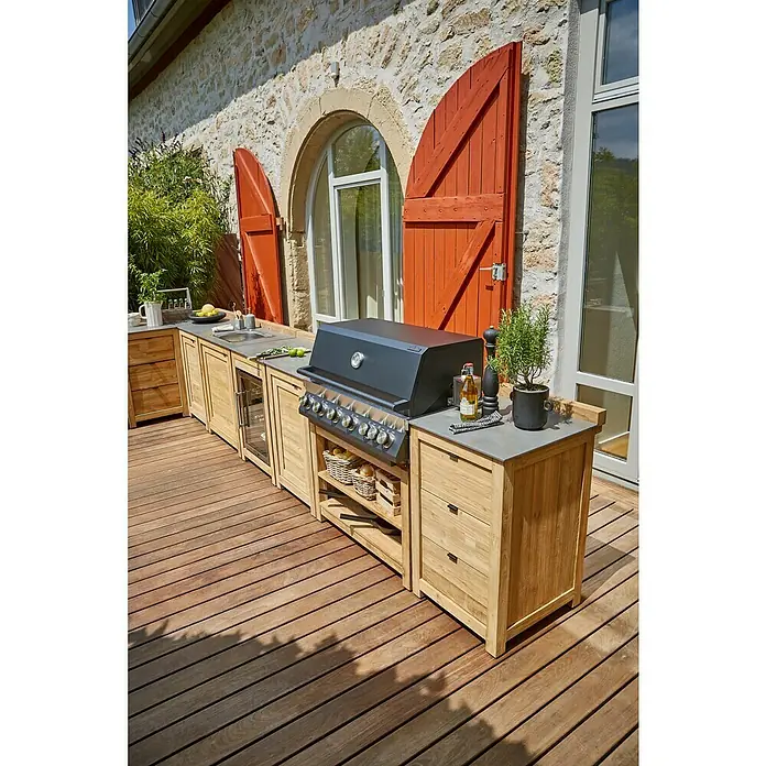 Sunfun Zoe Outdoorküchen-Modul Waschbecken - Braun, B x T x H: 80 x 63 x 96,7 cm, Teakholz - Bild einer modernen Outdoor-Küche mit Grill, Spüle und viel Stauraum auf einer Holzterrasse vor einem Steinhaus.