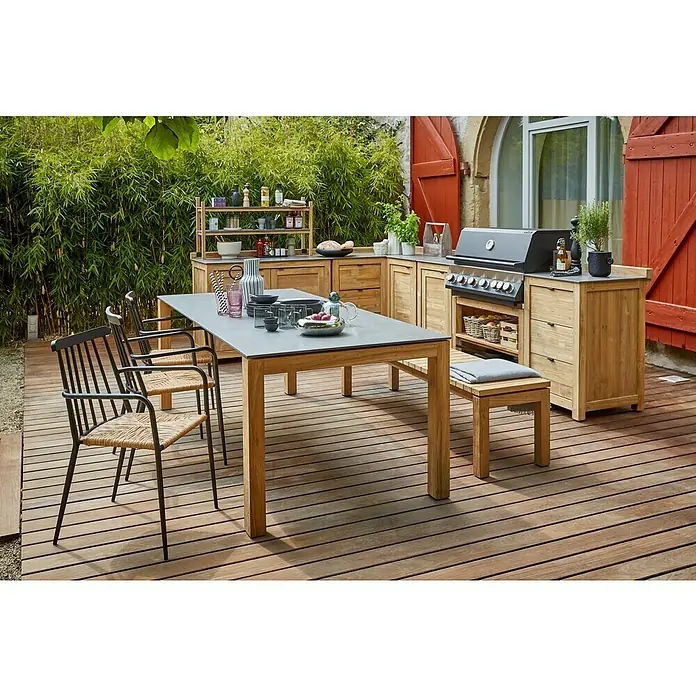 Sunfun Zoe Outdoorküchen-Modul Eckschrank - Braun, B x T x H: 120 x 120 x 92 cm, Teakholz - Ein modernes Gartenmöbelset mit Esstisch, Bank und Stühlen auf einer Holzterrasse, ergänzt durch eine Außenküche.