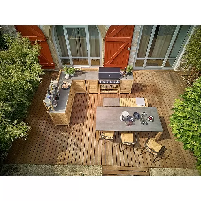 Sunfun Zoe Outdoorküchen-Modul Doppelschrank - Braun, B x T x H: 120 x 63 x 92 cm, Teakholz - Modulare Outdoor-Küche mit Holzschränken, Steinarbeitsplatten und Grill, auf einer Holzterrasse neben einem Esstisch mit Stühlen.