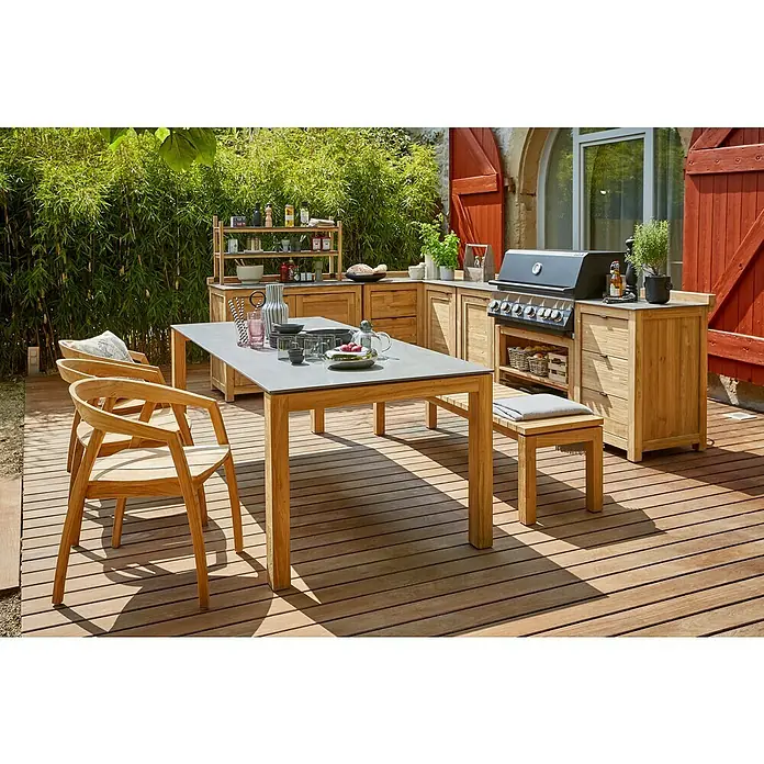 Sunfun Zoe Gartentisch - L x B x H: 220 x 100 x 77 cm, Keramik, Teak, Rechteckig, Naurbraun/Anthrazit - Ein stilvoller Outdoor-Essbereich mit einem robusten Esstisch und passenden Stühlen aus Holz, ergänzt durch eine moderne Küchenzeile im Hintergrund.
