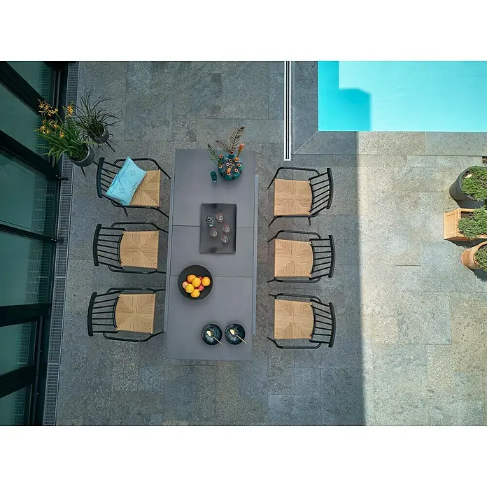 Envy Gartensessel Eva - Rattan/Geflecht, Stapelbar, Schwarz/Natur, B x T x H: 58 x 54 x 84 cm - Gartenmöbel-Set mit Esstisch und Stühlen auf einer Terrasse neben einem Pool. Das Set umfasst einen Tisch und sechs Korbstühle für entspannte Stunden im Freien.