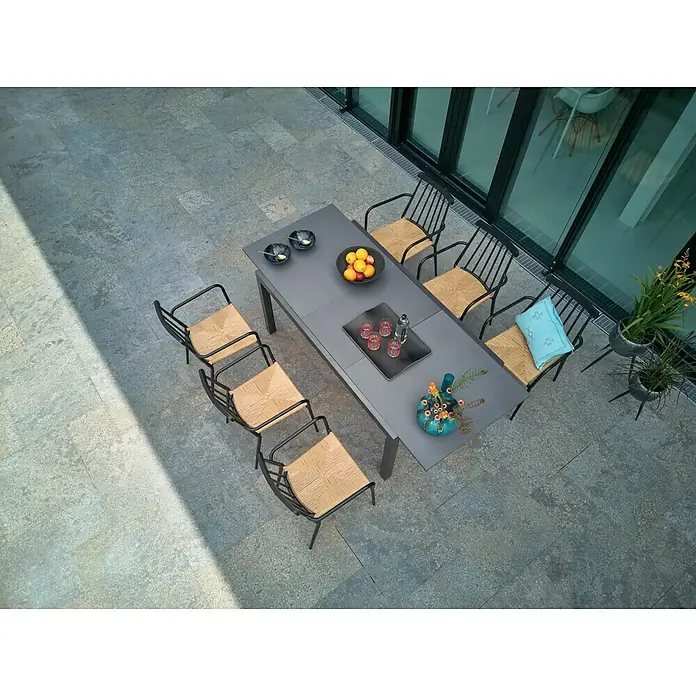 Sunfun Gartenmöbel-Set Maja/Eva - 7 -tlg., Glas, Anthrazit/Braun, Tischplatte ausziehbar - Luftaufnahme eines Esstisches mit Stühlen im Freien, dekoriert mit Obst, Getränken und einer Vase.
