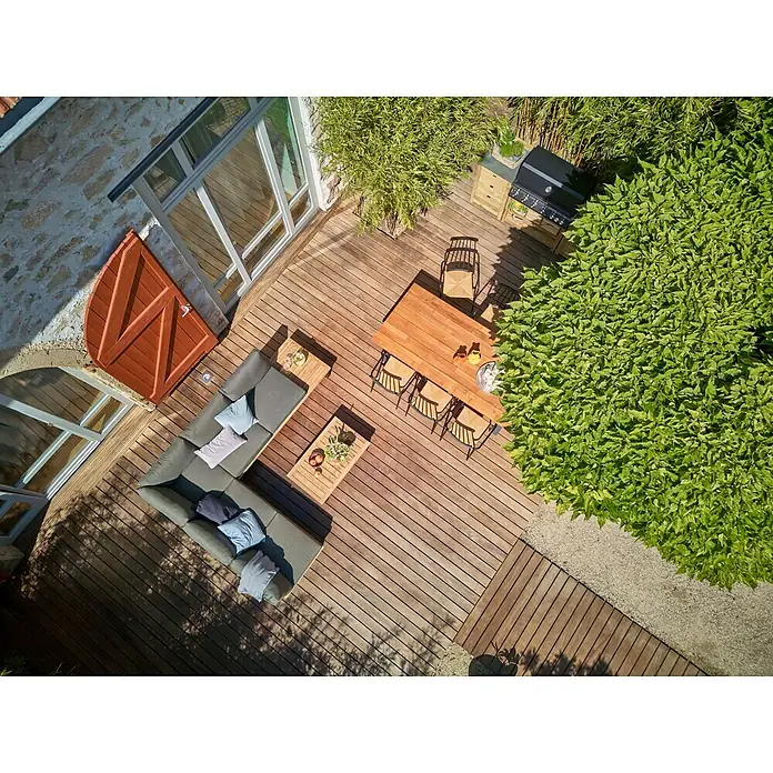 Sunfun Zoe Módulo de cocina exterior Armario con cajones - Marrón, An x Pr x Al: 58 x 63 x 92 cm, Madera de teca - Vista aérea de un elegante espacio al aire libre con muebles de salón, mesa de comedor y parrilla, rodeado de exuberante vegetación.