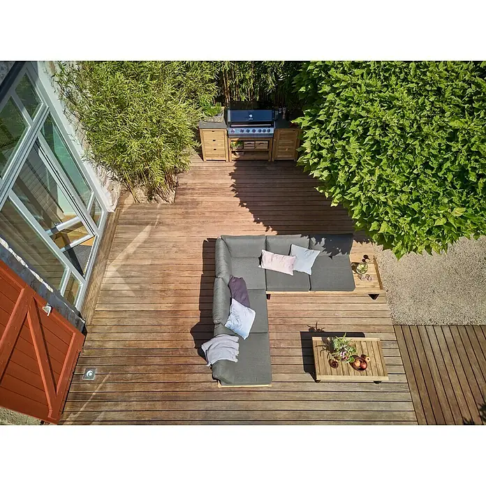 Sunfun Zoe Módulo de cocina exterior Armario con cajones - Marrón, An x Pr x Al: 58 x 63 x 92 cm, Madera de teca - Vista aérea de una elegante terraza de madera con parrilla, zona de estar y mesa, rodeada de exuberante vegetación para relajarse al aire libre.