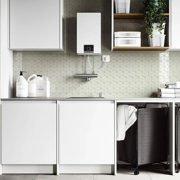 Vaillant Warmwasserspeicher VEN 10 O - 10 l, 2.000 W - Waschküchen-Szene mit weißen Schränken, Waschmittel, Boiler und Wäschekörben, die eine saubere und organisierte Atmosphäre vermitteln.