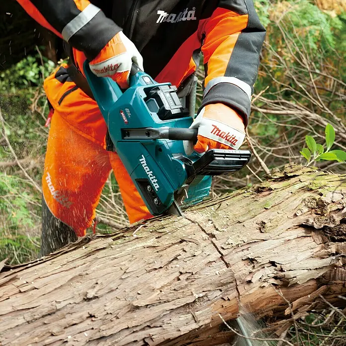 Makita XGT 40V max. Akku-Kettensäge UC011GT101 - 40 V, 5 Ah, Li-Ionen, 1 Akku, Schwertlänge: 35 cm - Eine Makita Akku-Kettensäge schneidet durch einen Baumstamm. Die Säge ist blaugrün und wird von einer Person mit Schutzkleidung bedient.
