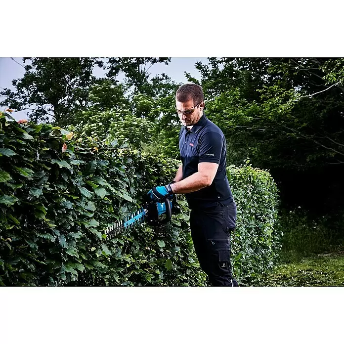 Makita LXT 18V Akku-Heckenschere DUH601Z - 18 V, Li-Ionen, Ohne Akku - Mann mit Schutzbrille schneidet mit einer türkis-schwarzen Heckenschere eine grüne Hecke.