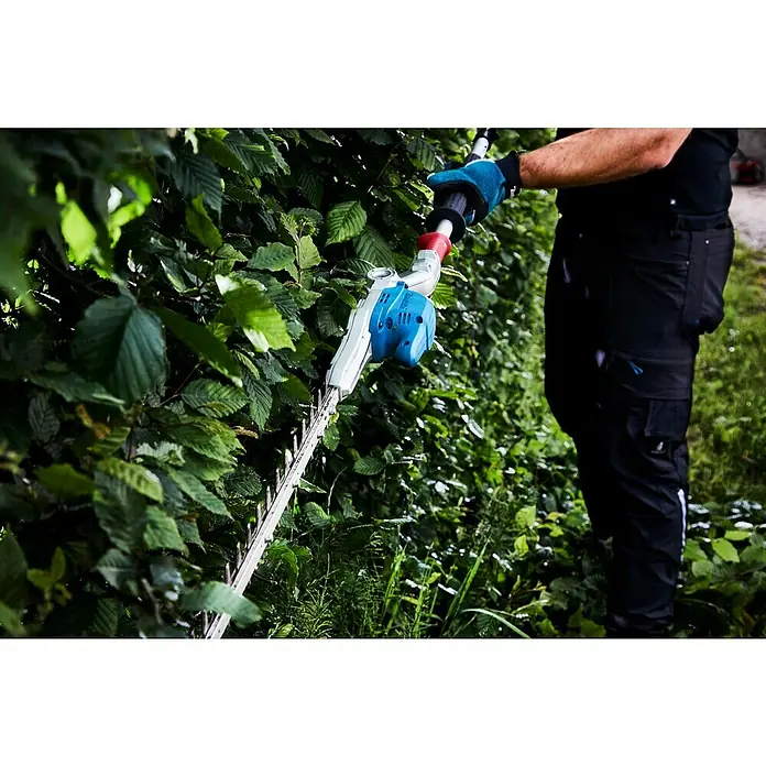 Makita LXT 18V Akku-Heckenschere DUN500WZ - 18 V, Li-Ionen, Ohne Akku - Eine Person, die eine elektrische Heckenschere benutzt, um eine Hecke zu schneiden. Das Gerät ist blau und weiß.