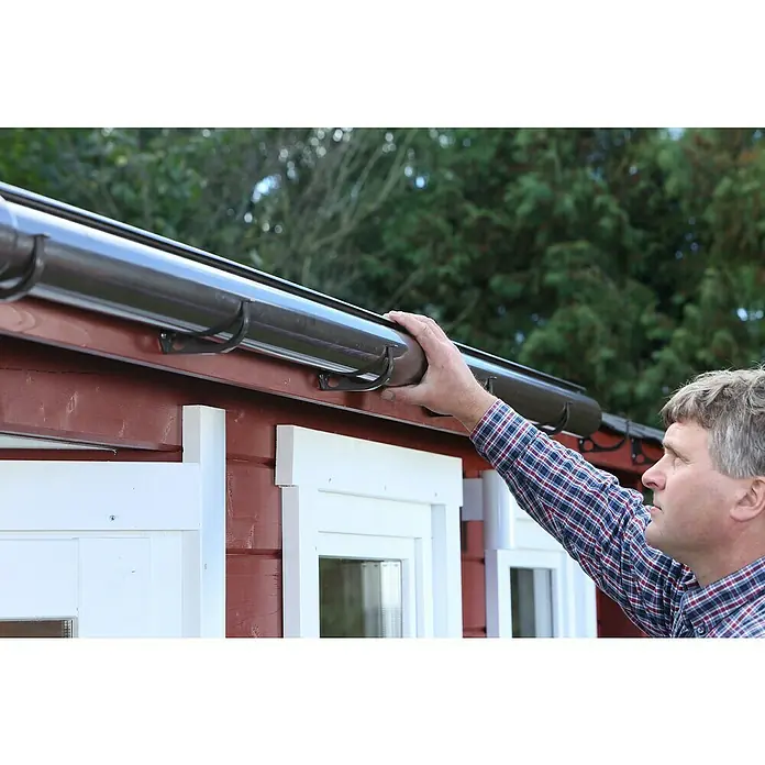 FunkeGruppe Dachrinne - Nennweite: 75 mm, Länge: 300 cm, Kunststoff, Anthrazit - Ein Mann überprüft eine braune Dachrinne, die an einem roten Gebäude mit weißen Fensterrahmen befestigt ist.