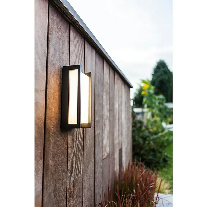Lutec Qubo Aplique exterior LED Qubo - 17,3 W, 7,1 x 11 x 22 cm, Antracita, IP54 - Lámpara de pared con marco negro y luz blanca cálida en una pared de madera en el exterior. Iluminación exterior moderna para acentos elegantes.