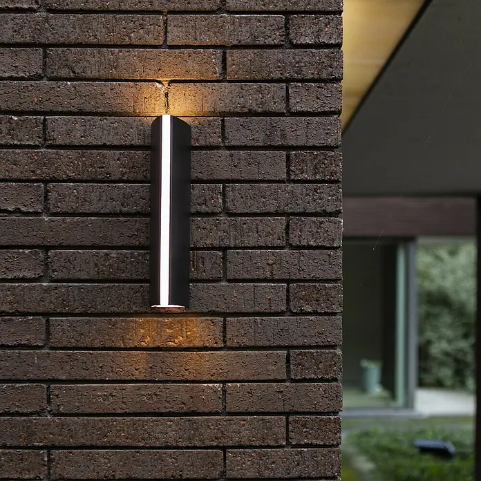 Lutec LED-Außenwandleuchte Leo - 14,5 W, 8,8 x 6,6 x 30 cm, Anthrazit, IP54 - Moderne Wandleuchte mit minimalistischem Design an einer Backsteinmauer.