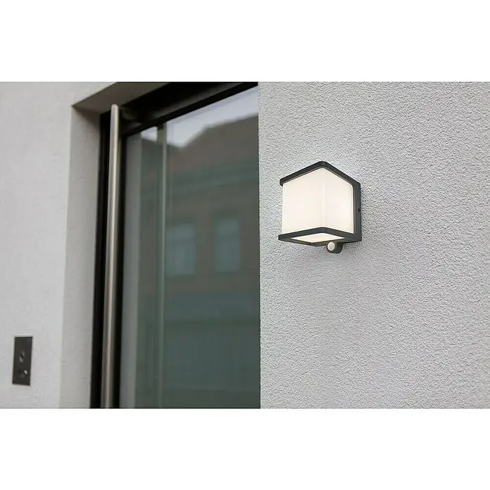 Lutec Doblo Solar-Außenwandleuchte - 7,5 W, L x B x H: 12,9 x 11 x 11 cm, IP54, 500 lm - Außenleuchte mit Bewegungsmelder an einer strukturierten Wand neben einer Tür.
