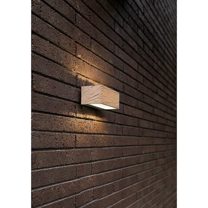 Lutec LED-Außenwandleuchte Gemini - 10,5 W, 14 x 8,9 x 6,5 cm, Anthrazit/holzfarben, IP54 - Moderne Wandleuchte mit Holzoptik an einer Backsteinmauer, die ein warmes, nach oben und unten gerichtetes Licht ausstrahlt.