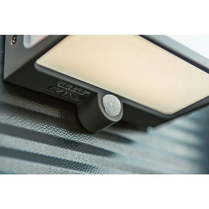 Lutec Doblo Solar-Außenwandleuchte - 12 W, L x B x H: 15 x 8,9 x 17 cm, Anthrazit, IP44, 1.000 lm - Nahaufnahme einer grauen Solarleuchte mit Bewegungssensor und Schalter für Aus, Ein, Auto und Dimmer, montiert an einer Wand.